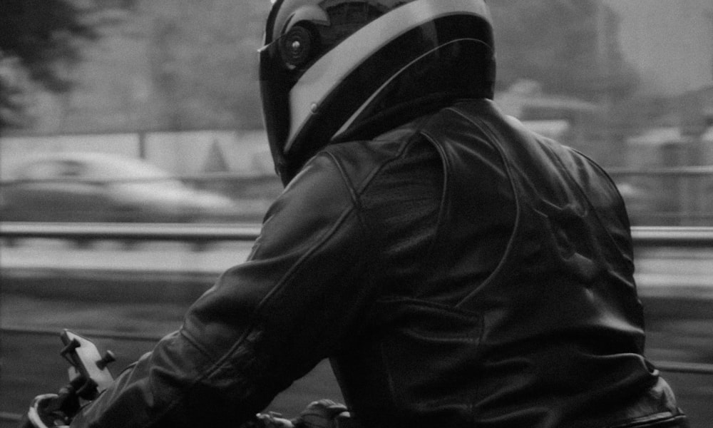 a man in a leather jacket riding a motorcycle