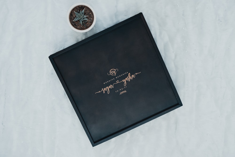 a black box with writing on it next to a potted plant