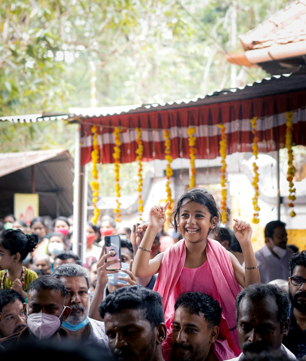 a woman in a pink sari standing in front of a crowd of people