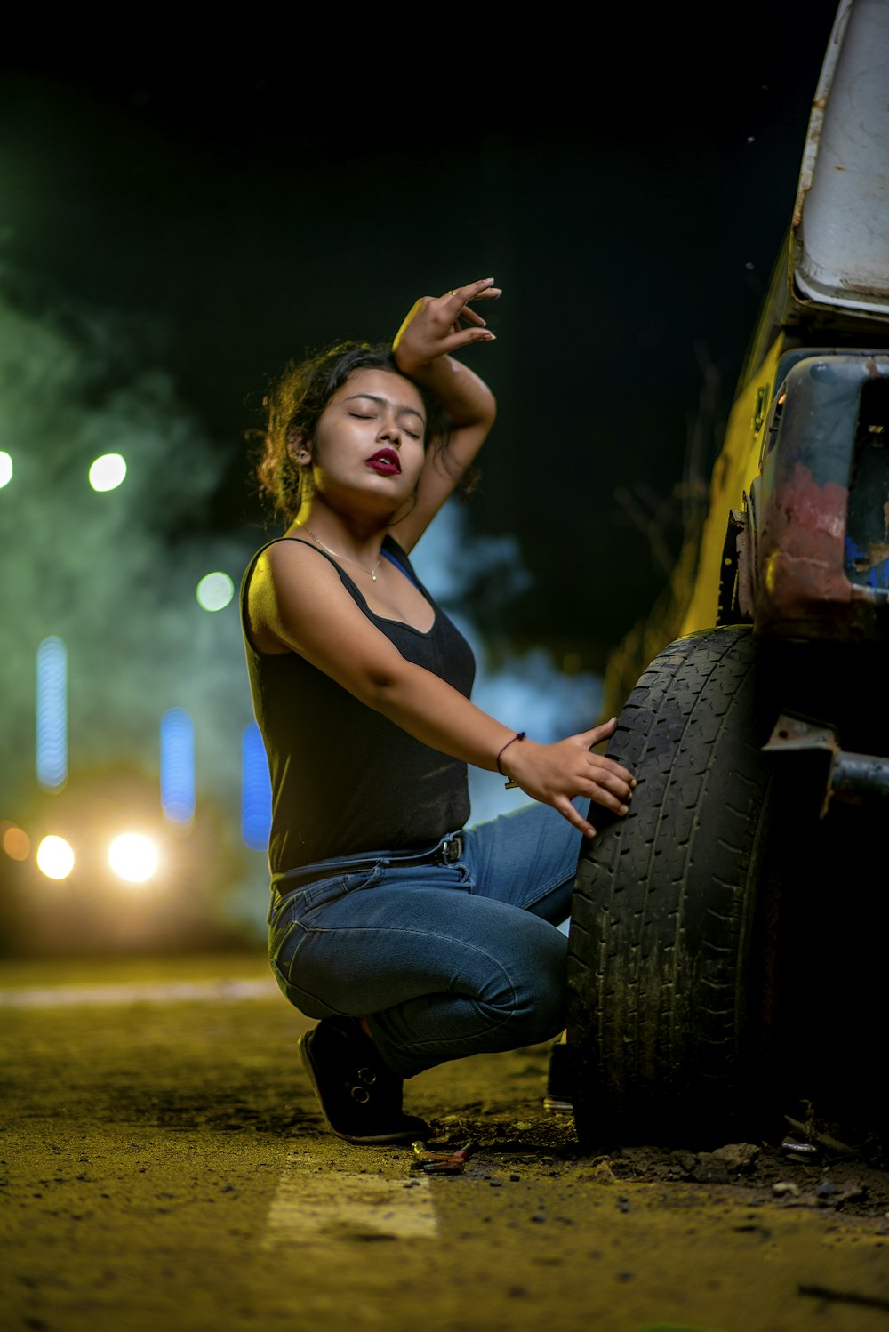 a woman sitting on the ground next to a tire