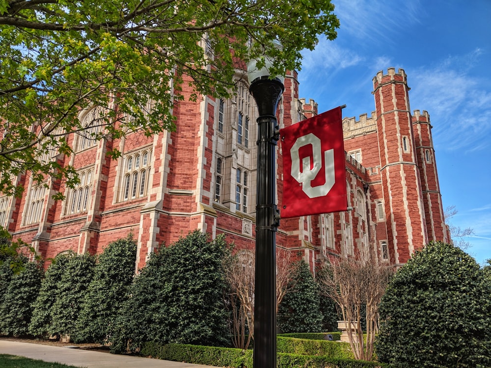 a red and white flag on a pole in front of a building