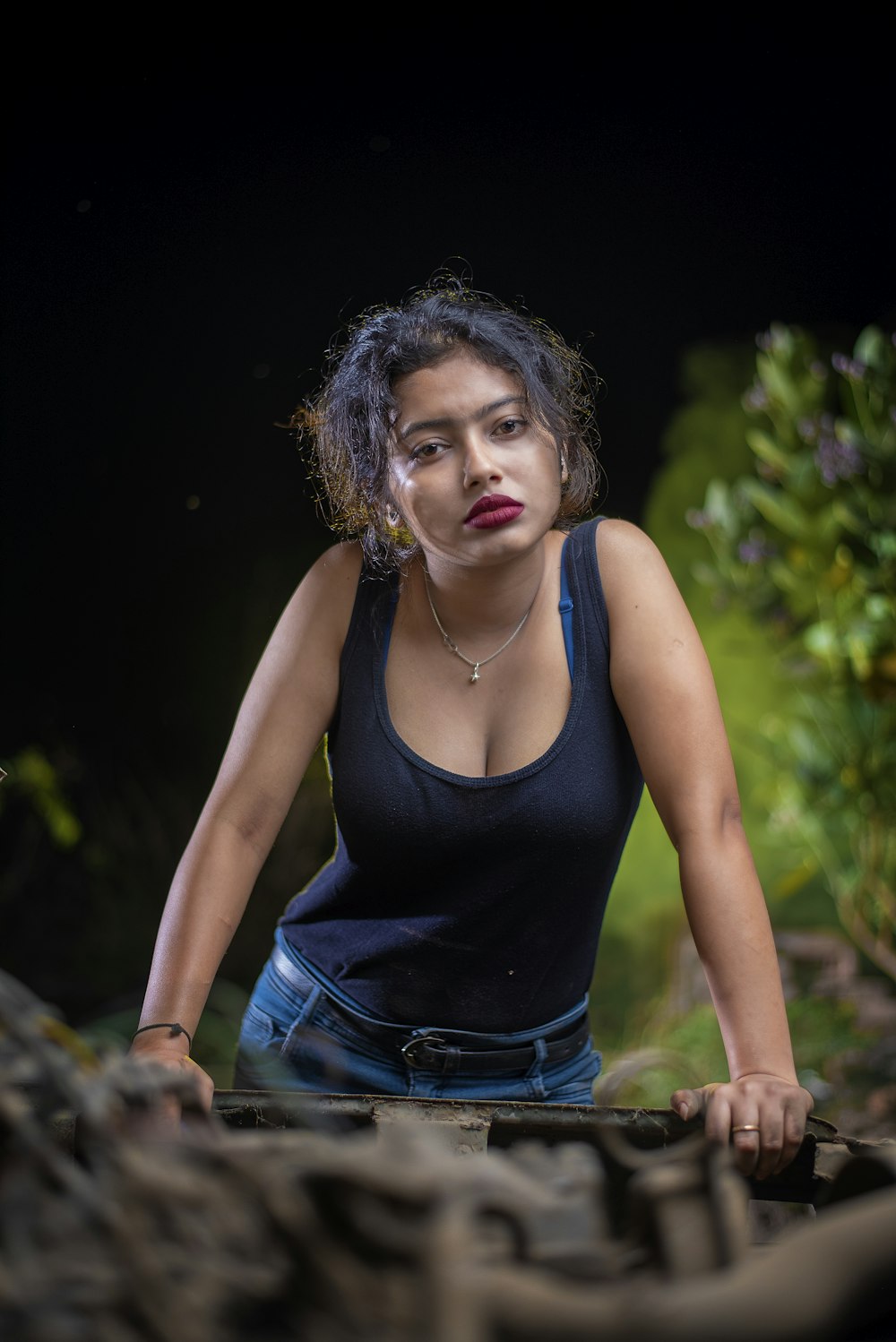 a woman in a black tank top is leaning on a tire