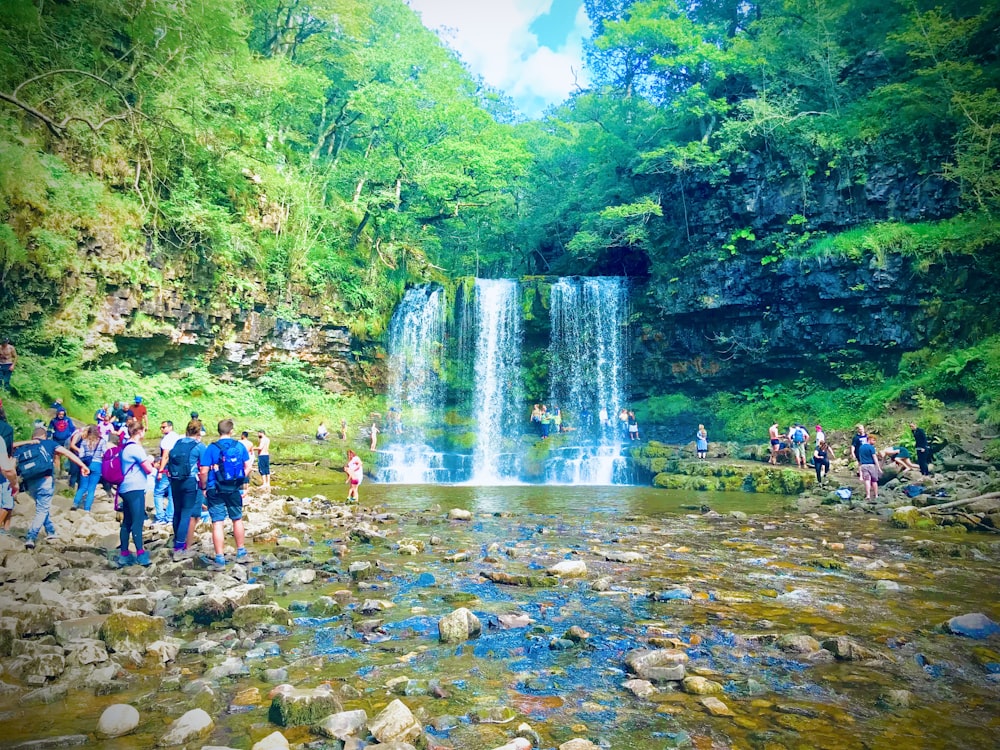 a group of people standing in front of a waterfall