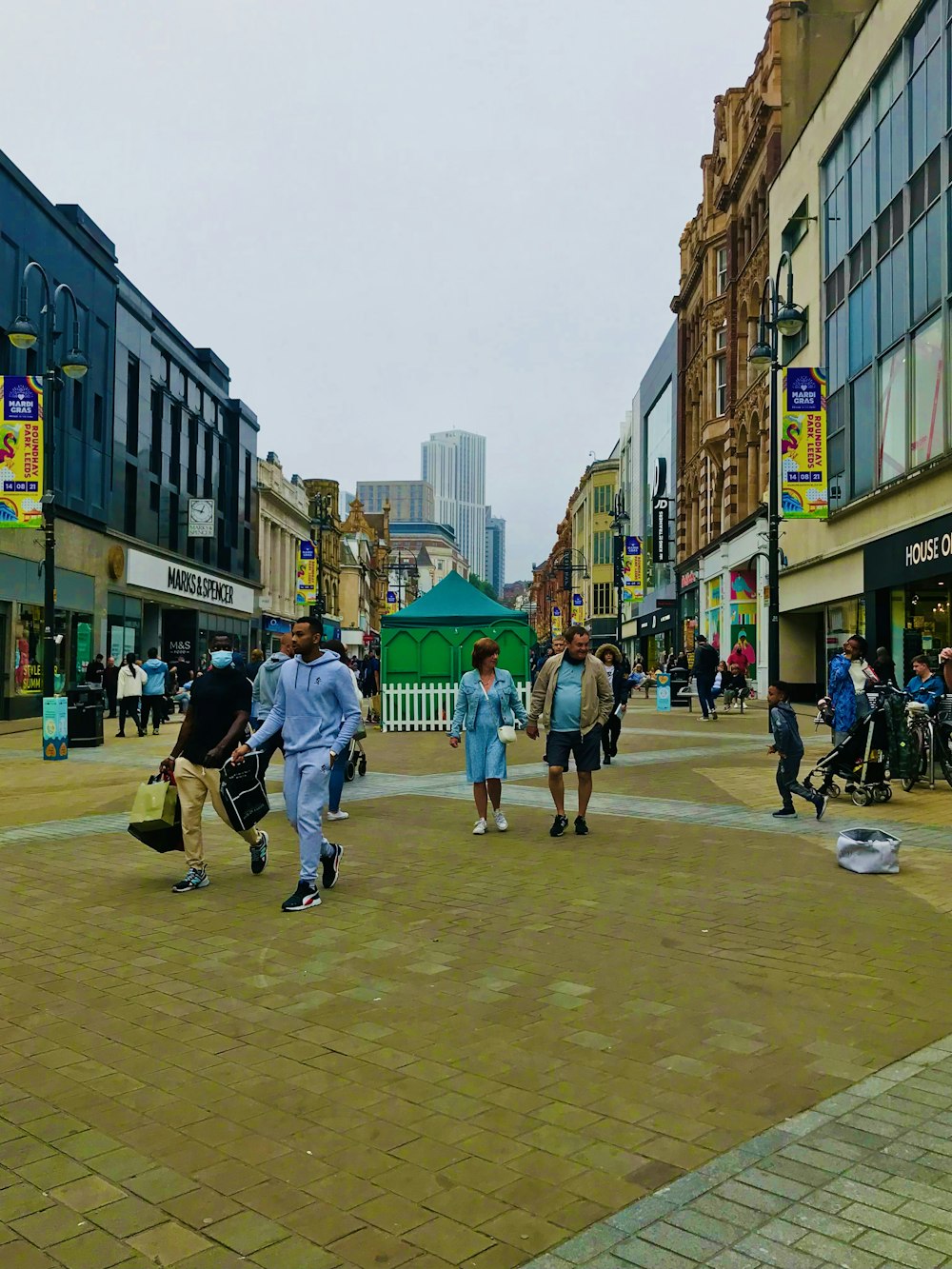 a group of people walking down a street next to tall buildings