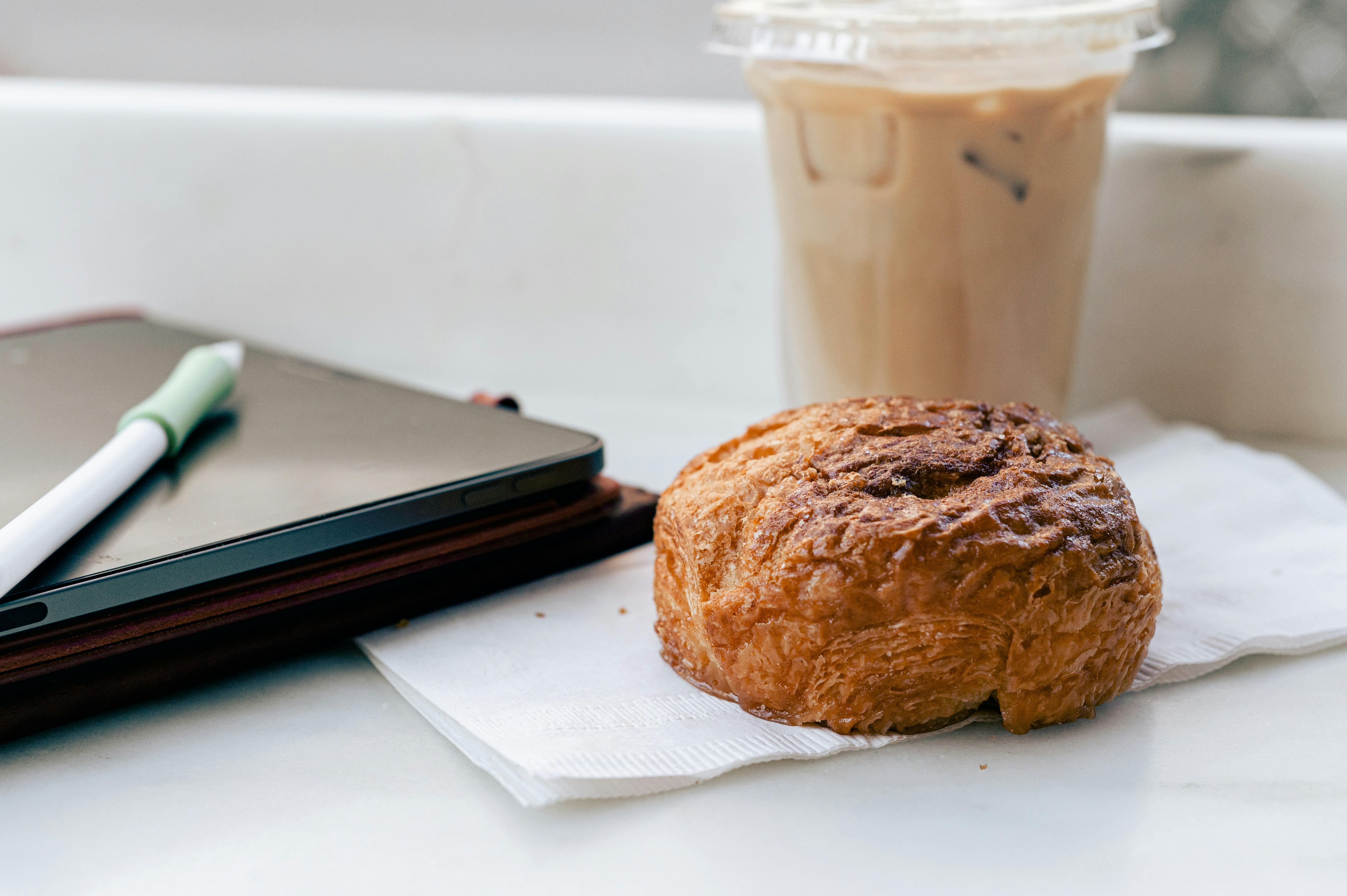 Iced latte beside a pastry on a napkin