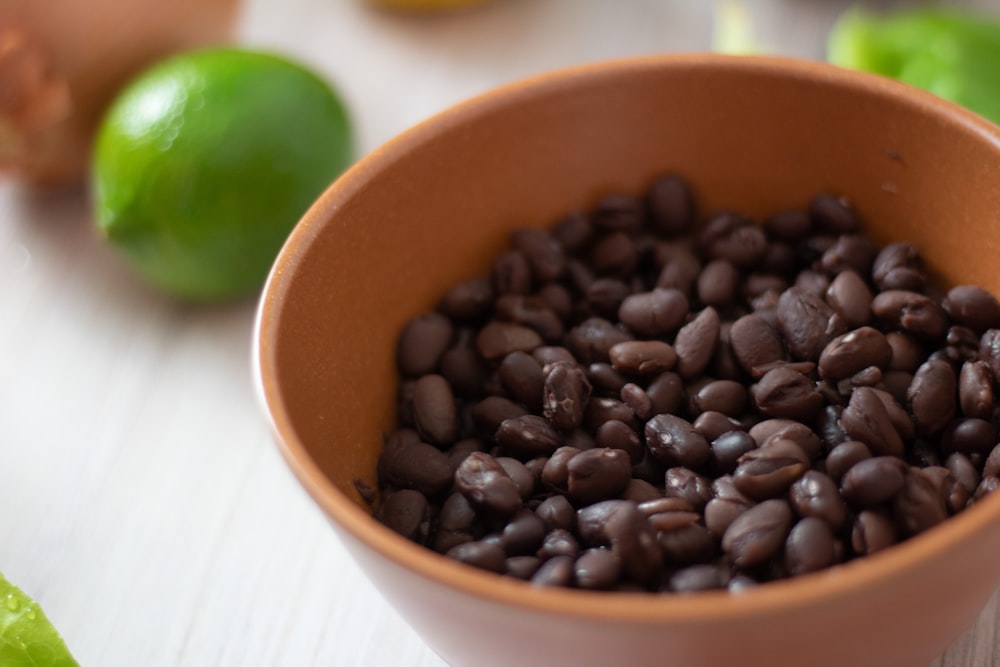 a bowl filled with black beans next to limes