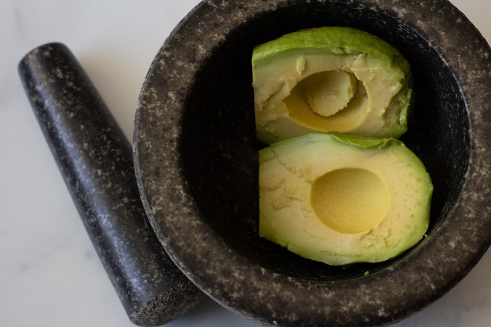 an avocado cut in half in a mortar bowl