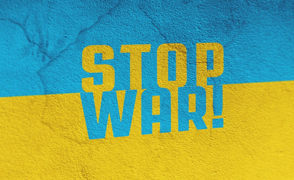 Un muro blu e giallo con le parole Stop War dipinte su di esso