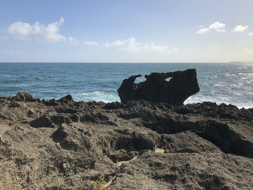 a rock formation on a beach with the ocean in the background