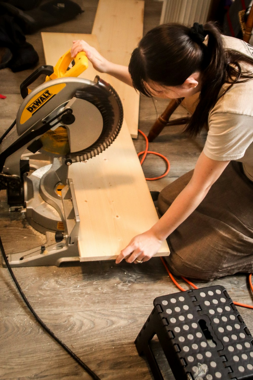 a woman using a circular saw to cut a piece of wood