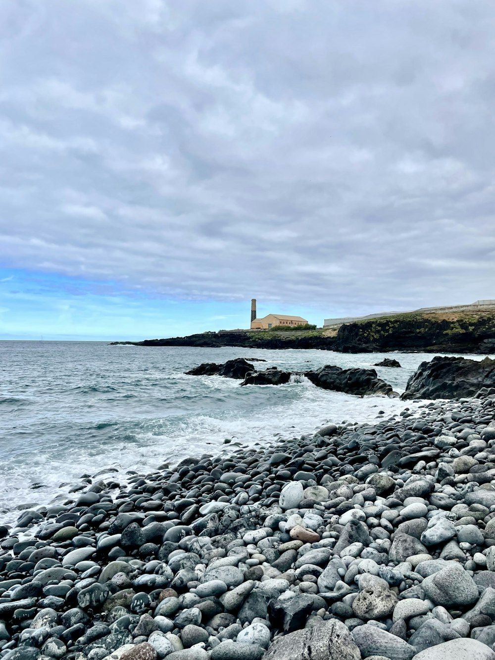 a rocky beach with a lighthouse in the distance
