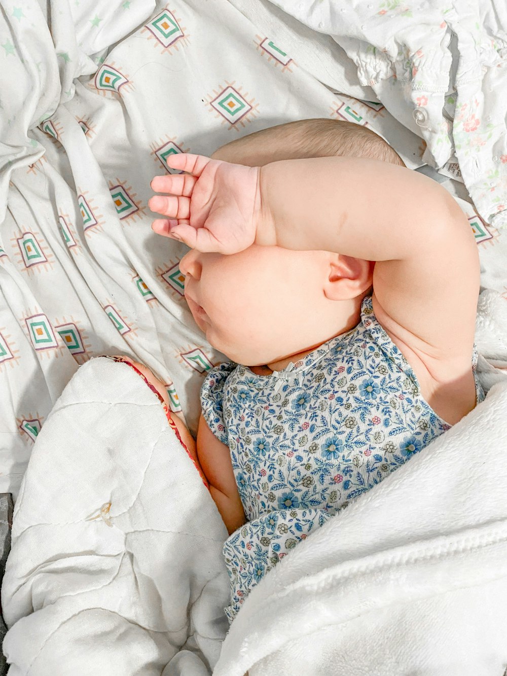 a baby laying on a bed with a white blanket