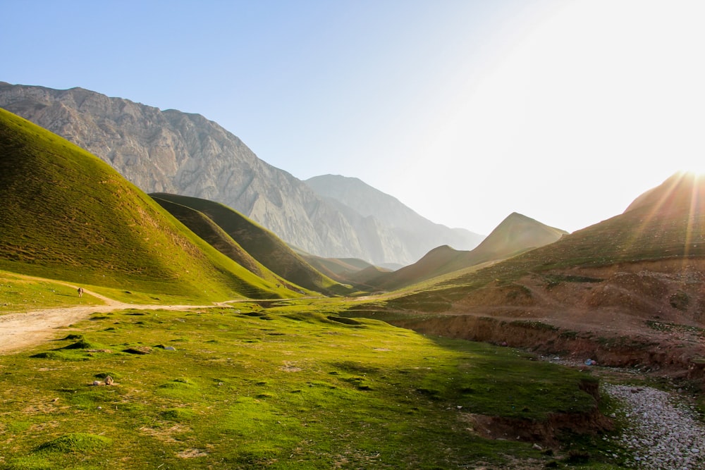 a dirt road going through a valley with mountains in the background