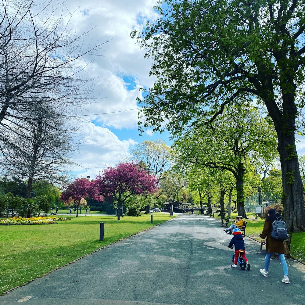 a woman and child walking down a tree lined road