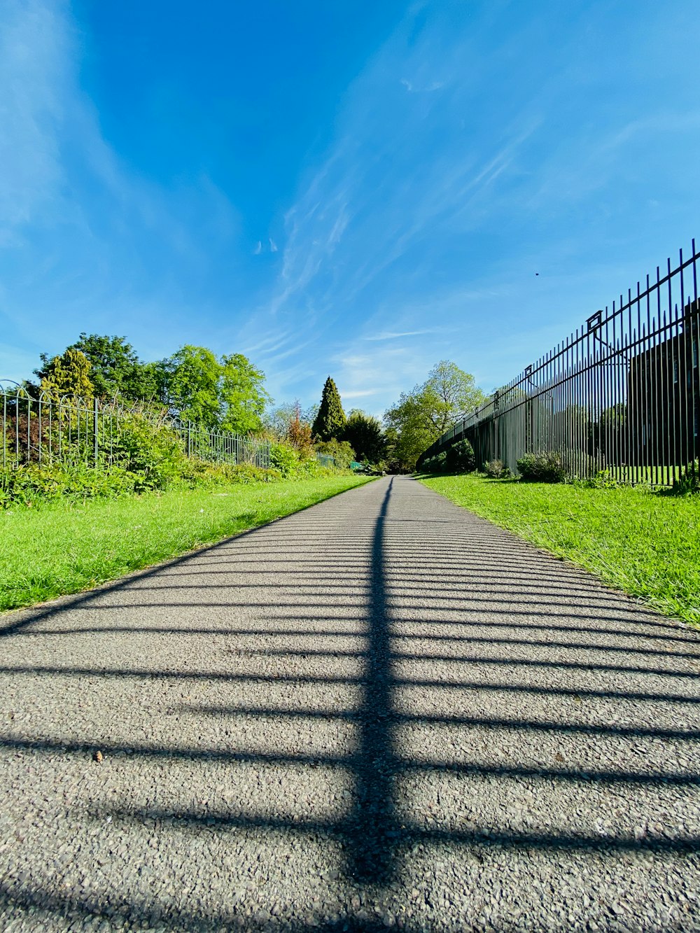 a street with a fence and a green field