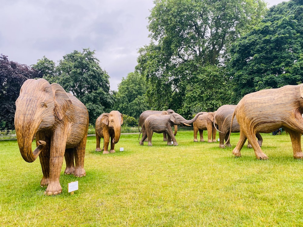 a herd of elephants walking across a lush green field