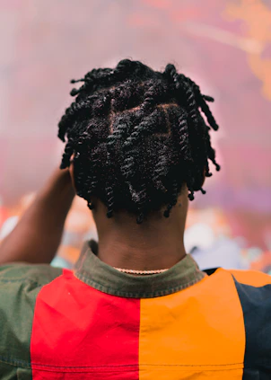 a person with dreadlocks standing in front of a painting