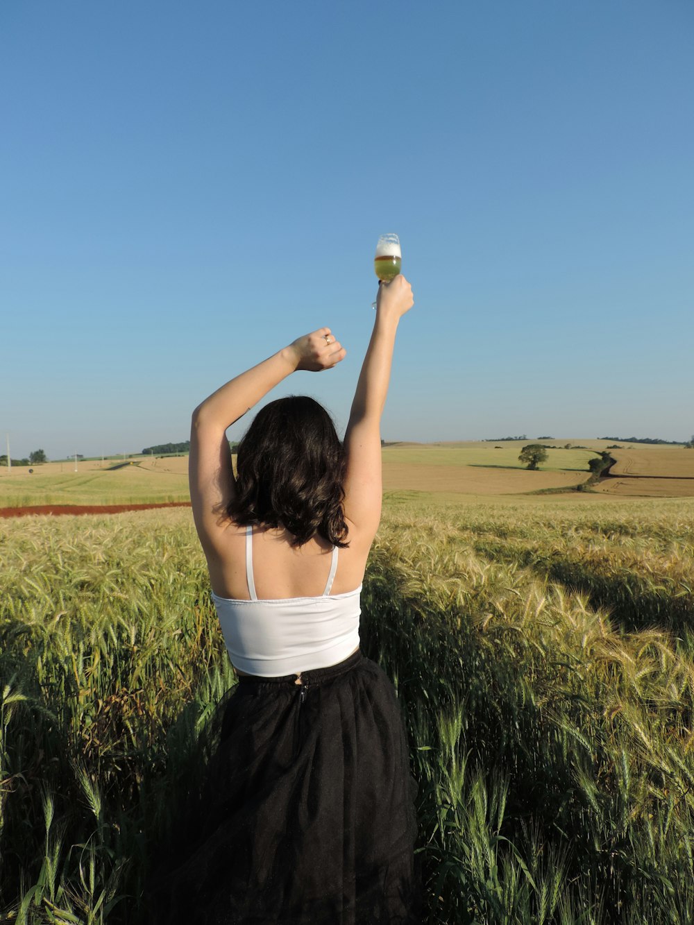 a woman standing in a field holding a cup