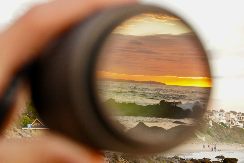 a person holding a magnifying glass looking at a beach