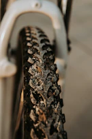 Close-up of a gravel bike tire splattered with mud on a forest path