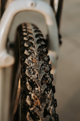 Close-up of a cyclist's muddy tire spinning fast over rocky terrain.