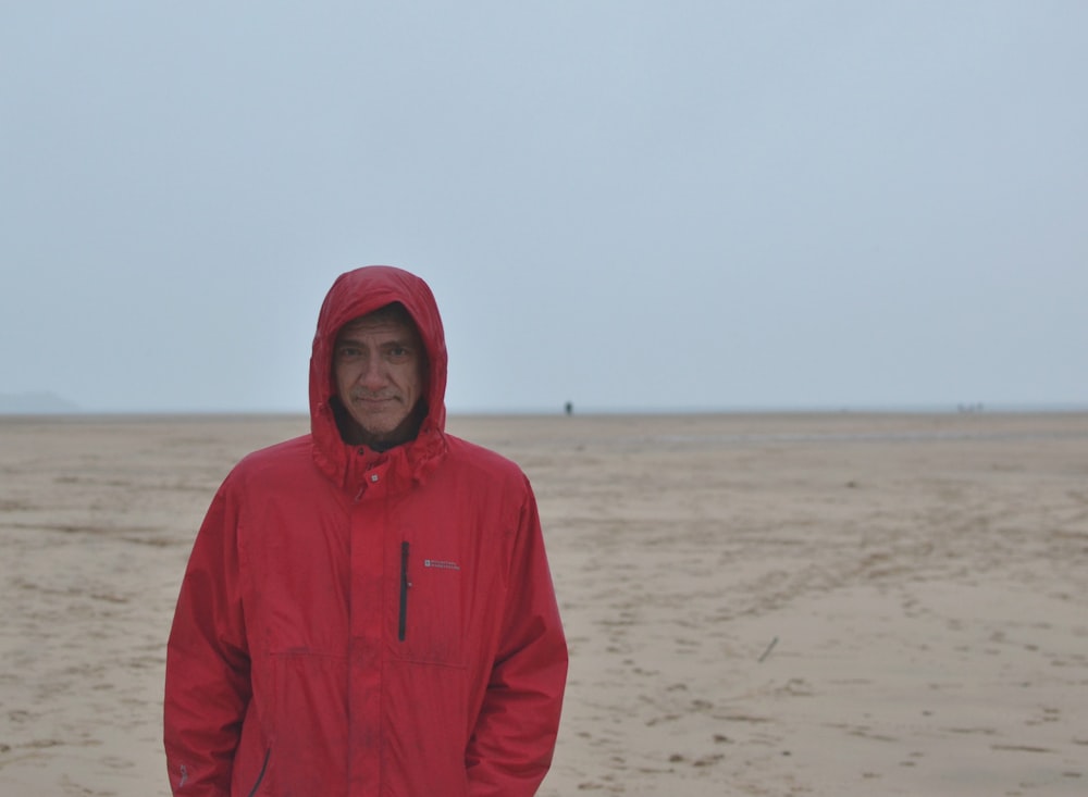 a man in a red jacket standing on a beach