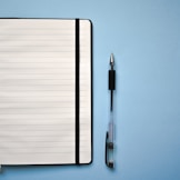 a notepad and a pen on a blue surface