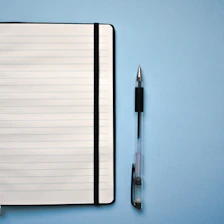 a notepad and a pen on a blue surface