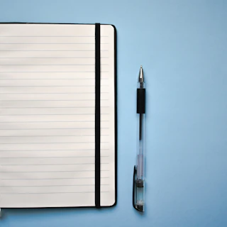 a notepad and a pen on a blue surface