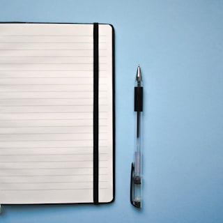 a notepad and a pen on a blue surface