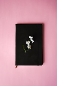 A soft blush pink notebook open with a pen ready to check off tasks.