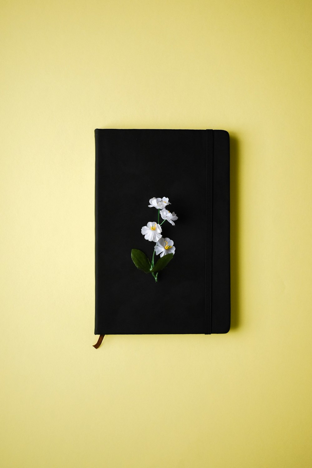 a black notebook with a flower on top of it