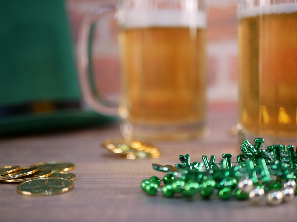 a table topped with two mugs of beer and gold coins