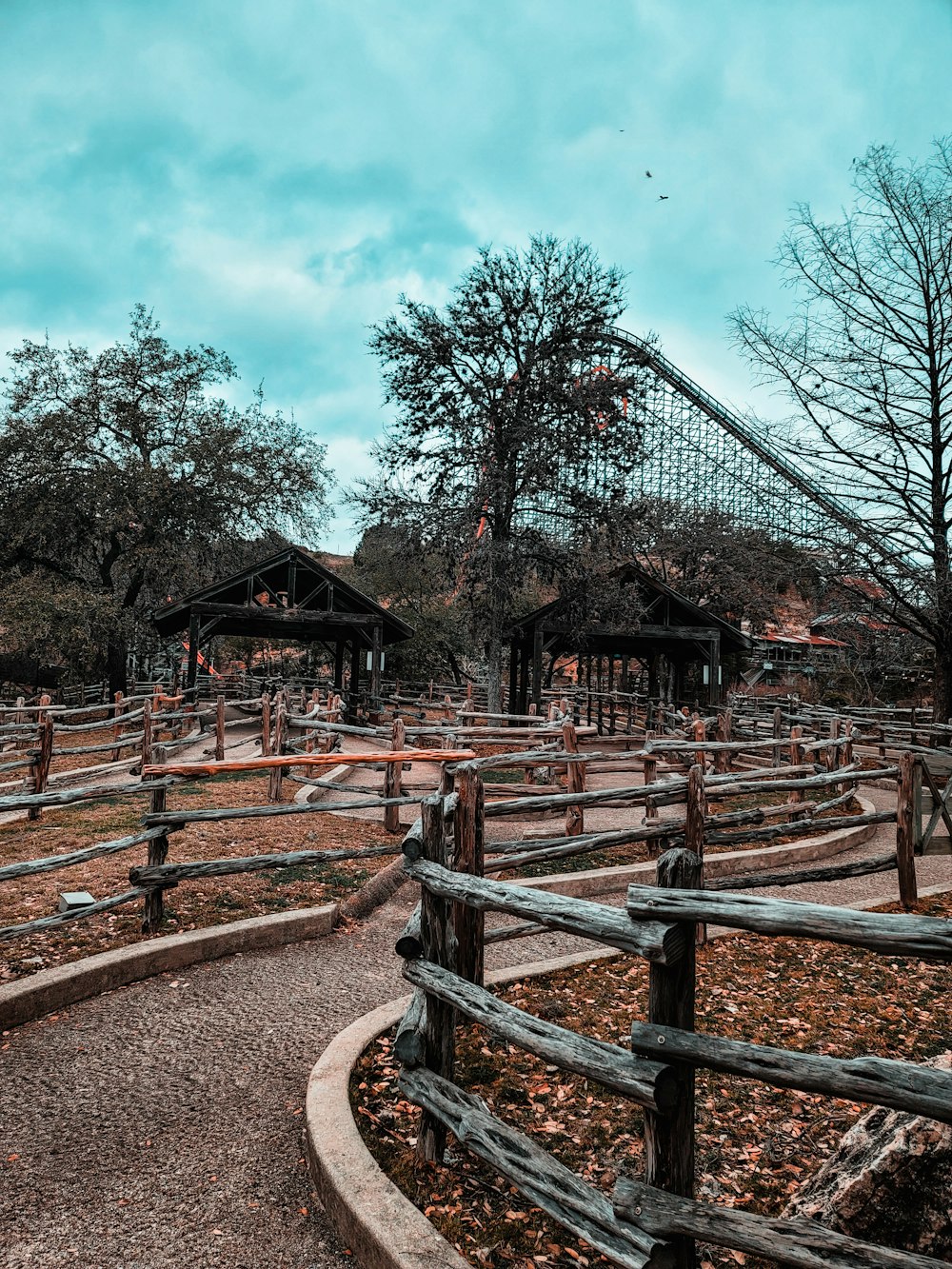 a wooden fenced in area with a roller coaster in the background