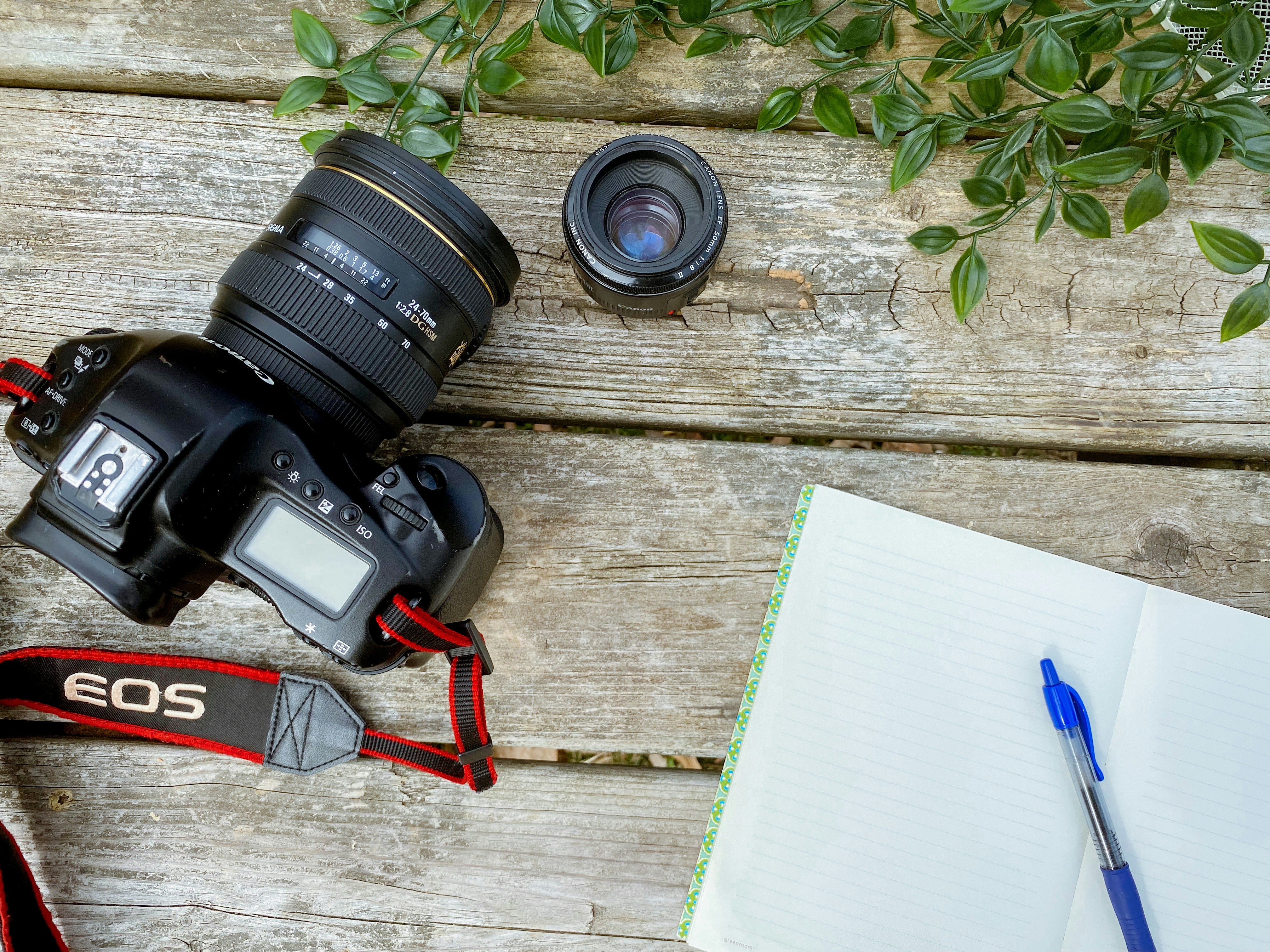 a camera and a notebook on a wooden table