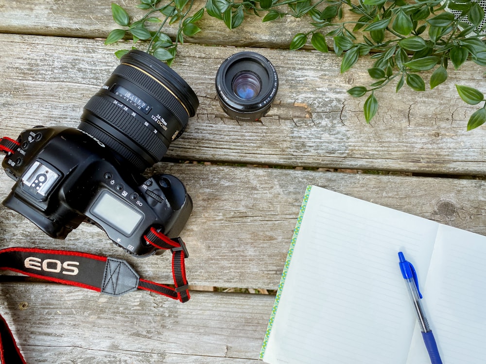 a camera and a notebook on a wooden table