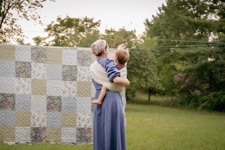 a woman holding a baby next to a quilt