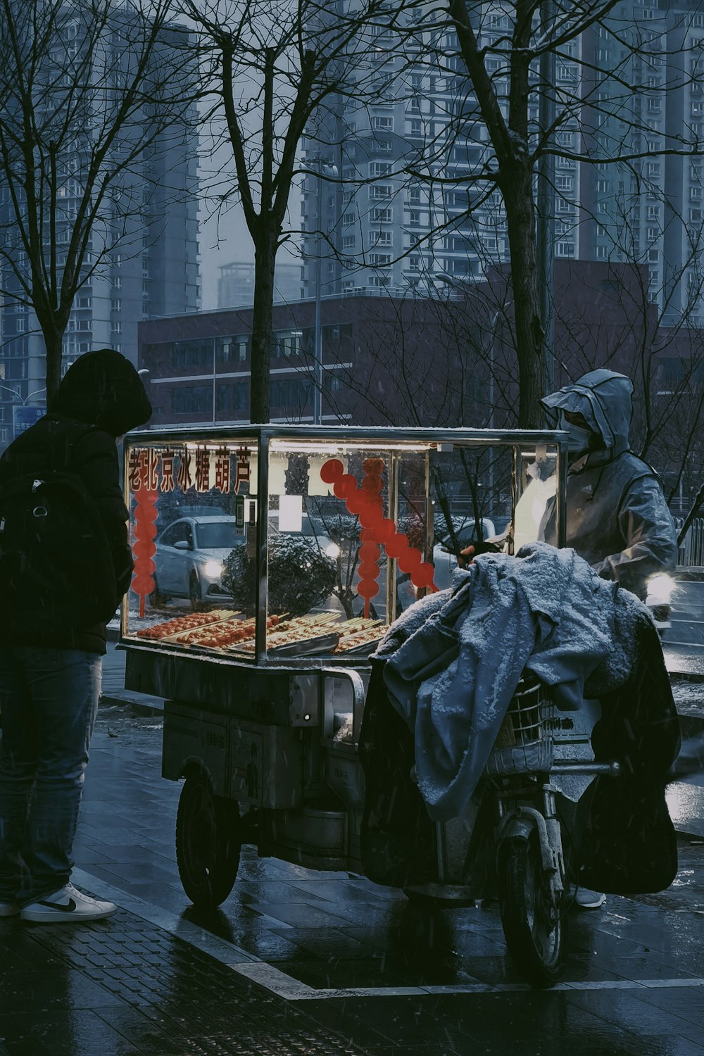 a man standing next to a food cart on a street