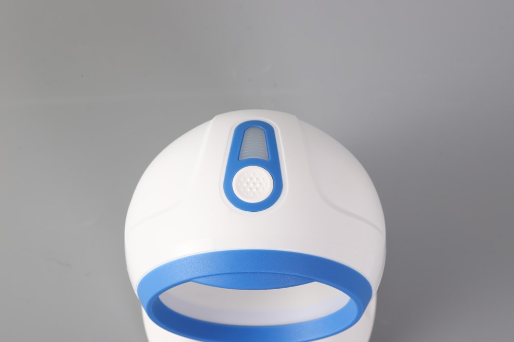 a white and blue alarm clock on a gray surface