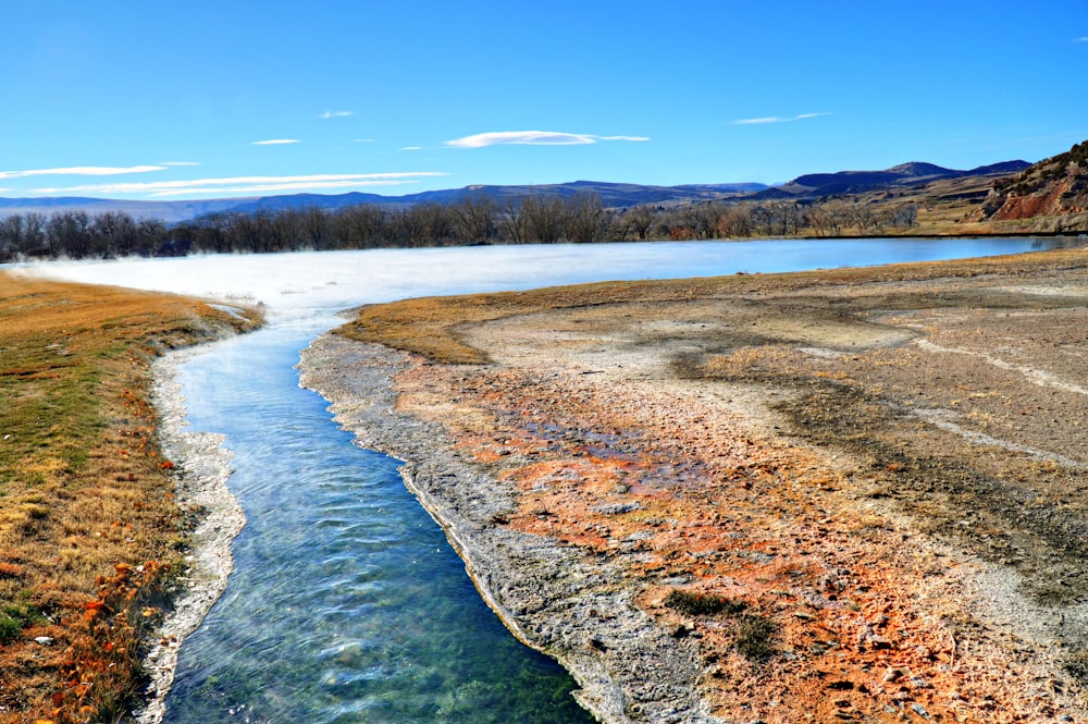 a river running through a dry grass covered field