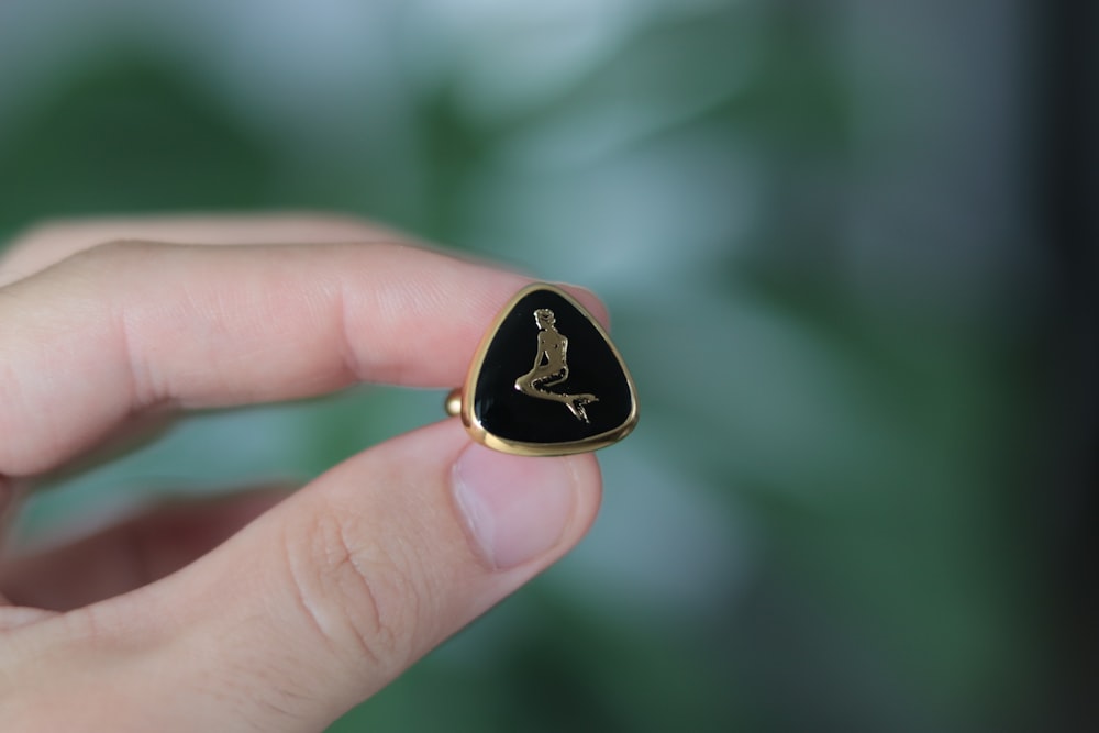 a person holding a small black and gold ring