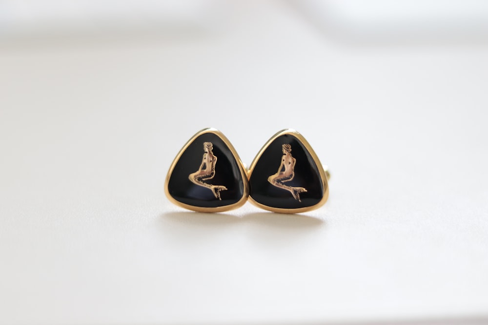 a pair of earrings with a woman sitting on top of it
