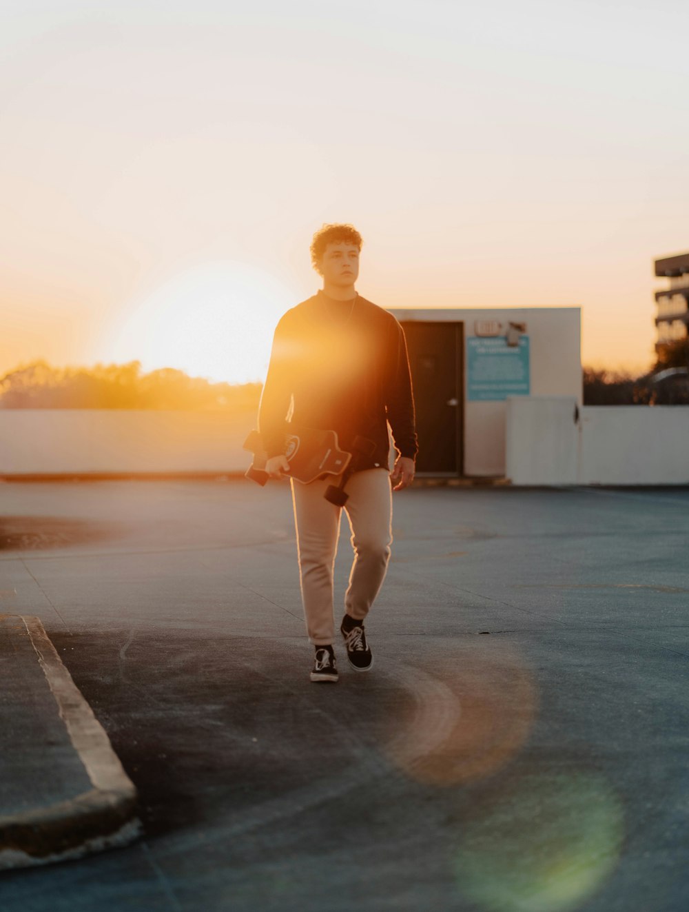 a man walking across a parking lot at sunset