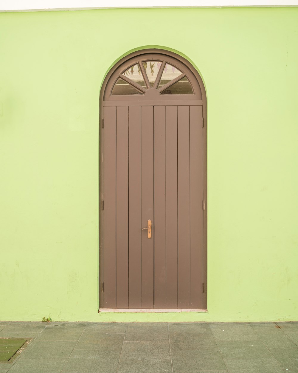 a large brown door on the side of a green building