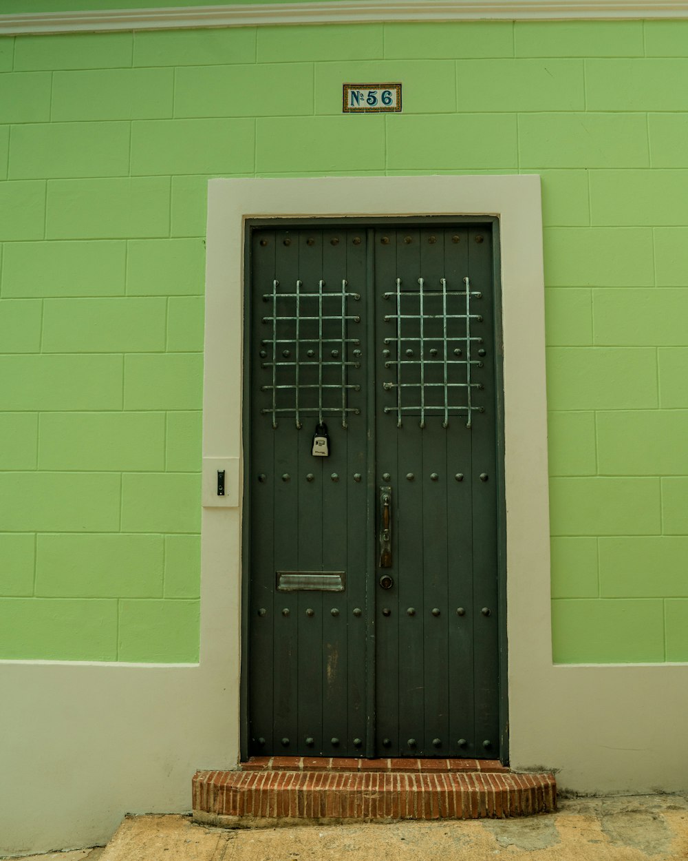 a green building with a black door and a brick step