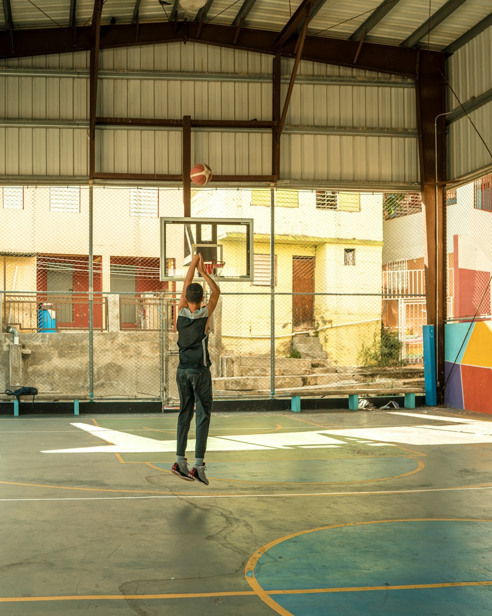 Un hombre parado en una cancha de baloncesto sosteniendo una pelota de baloncesto