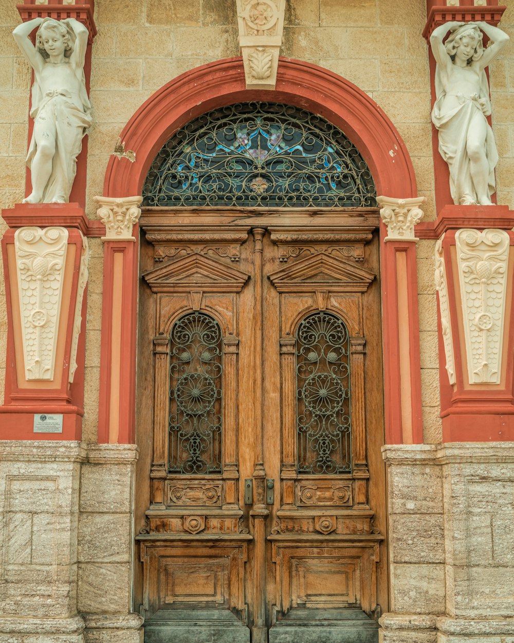 a large wooden door with statues above it