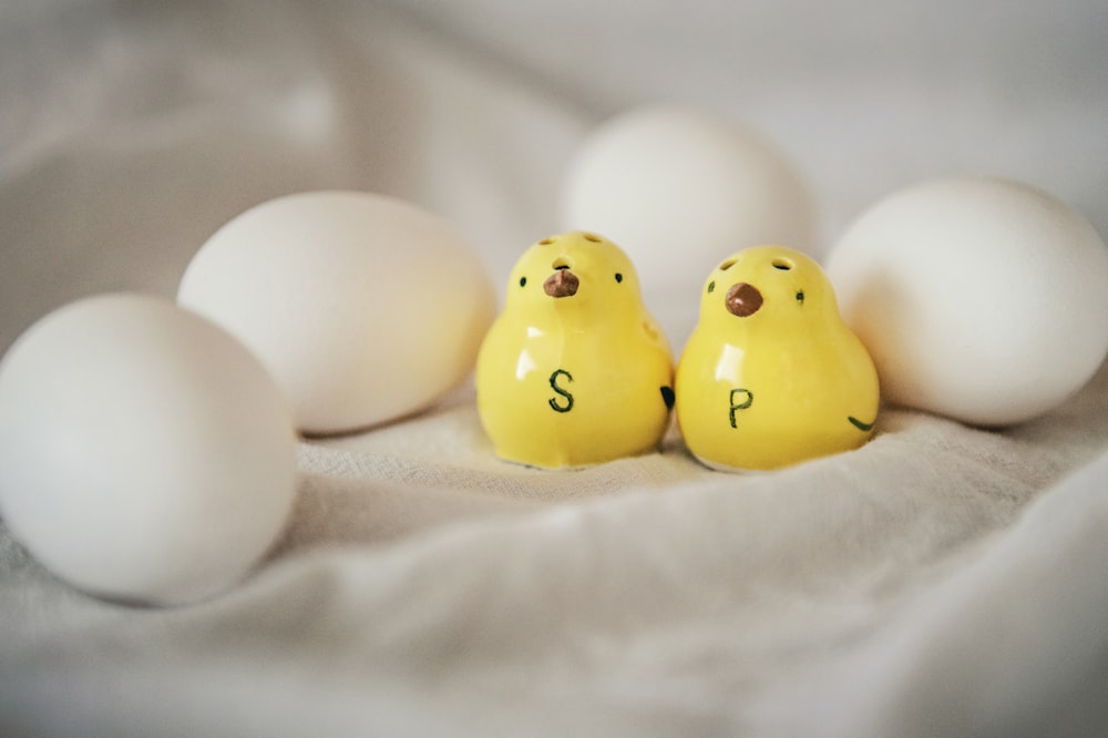 a couple of yellow chicks sitting next to some white eggs