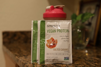Athlete mixing plant-based protein powder into a shaker bottle in a bright gym setting, emphasizing natural ingredients.