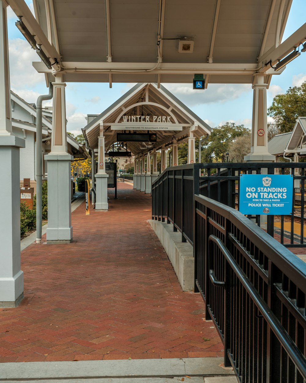 a walkway leading to a train station with a sign on it